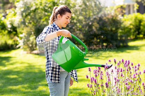 Image of young woman watering flowers at garden