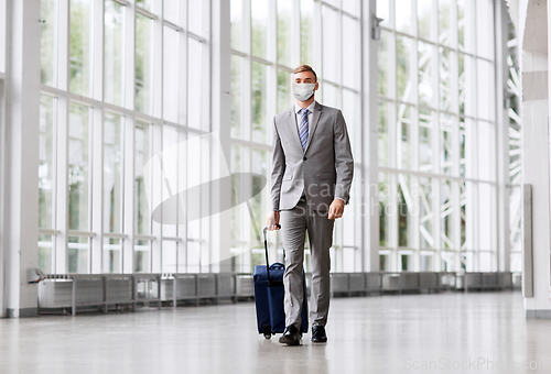 Image of businessman in mask with travel bag at airport