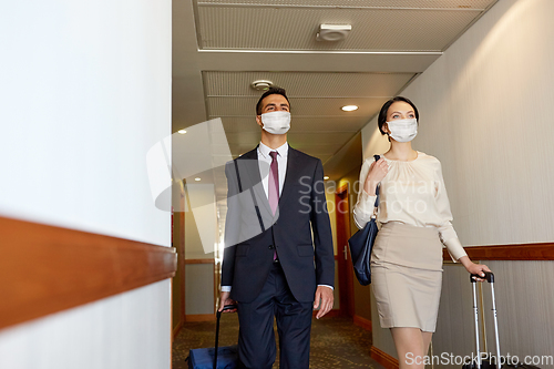 Image of business team in masks with travel bags at hotel