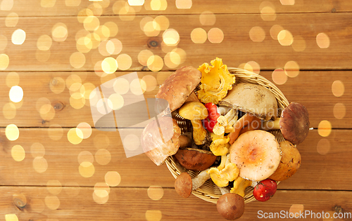 Image of basket of different edible mushrooms on wood