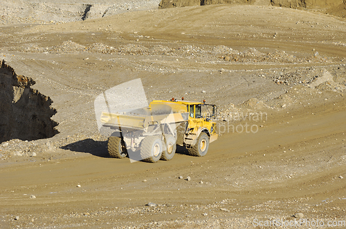 Image of Yellow dump truck working in gravel pit