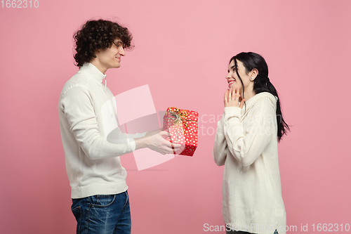 Image of Young, beautiful couple in love on pink studio background. Valentine\'s Day, love and emotions concept