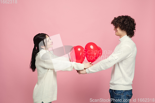 Image of Young, beautiful couple in love on pink studio background. Valentine\'s Day, love and emotions concept