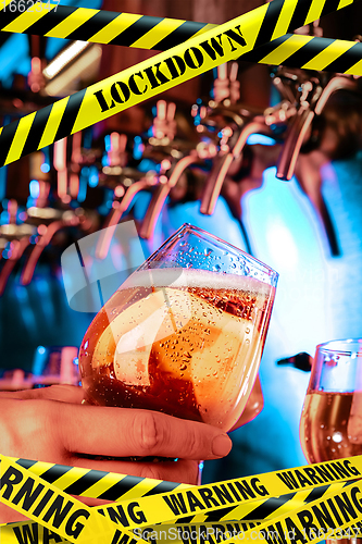 Image of Hand of bartender pouring a beer in tap with bounding tapes Lockdown, Coronavirus, Quarantine, Warning - closing bars and nightclubs during pandemic