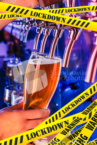 Image of Hand of bartender pouring a beer in tap with bounding tapes Lockdown, Coronavirus, Quarantine, Warning - closing bars and nightclubs during pandemic