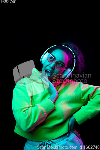 Image of African-american woman\'s portrait isolated on dark studio background in multicolored neon light