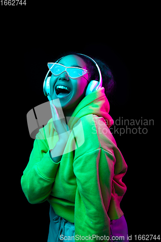 Image of African-american woman\'s portrait isolated on dark studio background in multicolored neon light