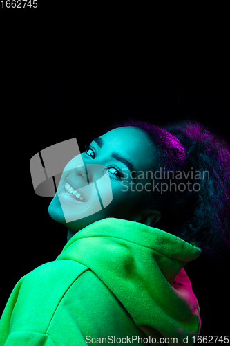 Image of African-american woman\'s portrait isolated on dark studio background in multicolored neon light