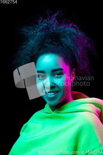 Image of African-american woman\'s portrait isolated on dark studio background in multicolored neon light