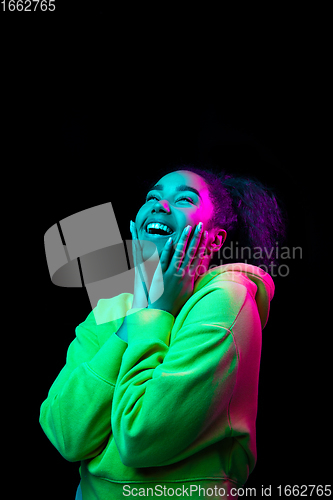 Image of African-american woman\'s portrait isolated on dark studio background in multicolored neon light