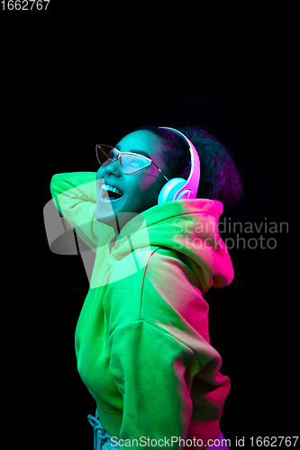 Image of African-american woman\'s portrait isolated on dark studio background in multicolored neon light