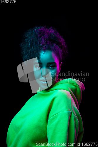 Image of African-american woman\'s portrait isolated on dark studio background in multicolored neon light