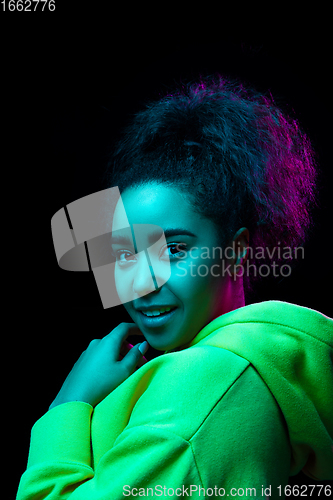 Image of African-american woman\'s portrait isolated on dark studio background in multicolored neon light