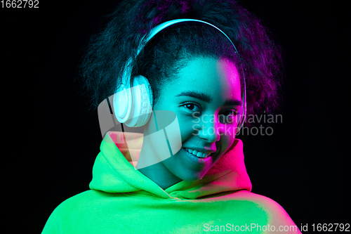 Image of African-american woman\'s portrait isolated on dark studio background in multicolored neon light