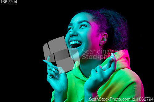 Image of African-american woman\'s portrait isolated on dark studio background in multicolored neon light