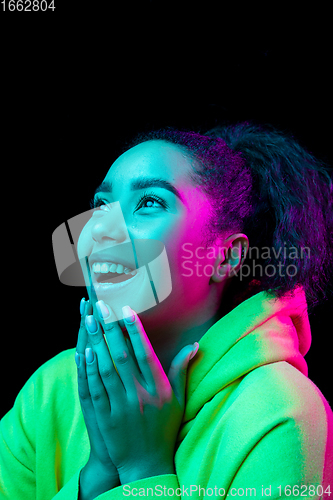 Image of African-american woman\'s portrait isolated on dark studio background in multicolored neon light