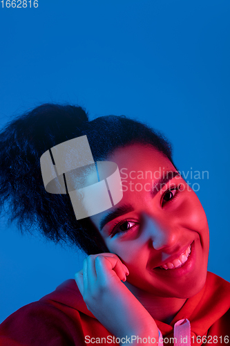 Image of African-american woman\'s portrait isolated on blue studio background in multicolored neon light