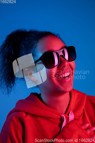 Image of African-american woman\'s portrait isolated on blue studio background in multicolored neon light