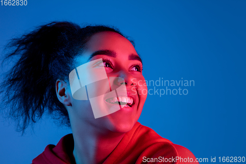 Image of African-american woman\'s portrait isolated on blue studio background in multicolored neon light