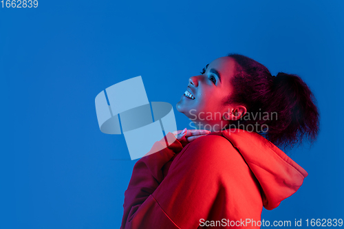 Image of African-american woman\'s portrait isolated on blue studio background in multicolored neon light