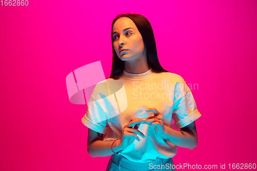 Image of Caucasian beautiful woman\'s portrait isolated on pink studio background in multicolored neon light