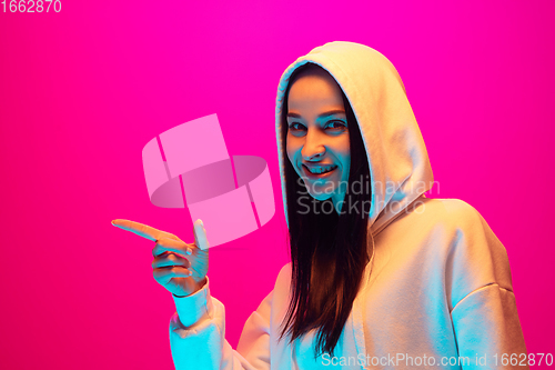 Image of Caucasian beautiful woman\'s portrait isolated on pink studio background in multicolored neon light
