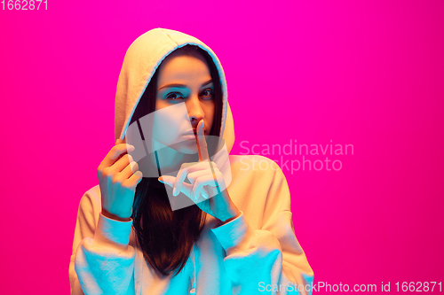 Image of Caucasian beautiful woman\'s portrait isolated on pink studio background in multicolored neon light