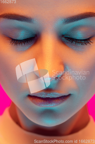 Image of Caucasian beautiful woman\'s portrait isolated on pink studio background in multicolored neon light