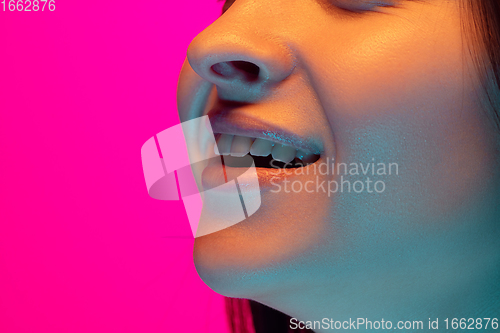 Image of Caucasian beautiful woman\'s portrait isolated on pink studio background in multicolored neon light