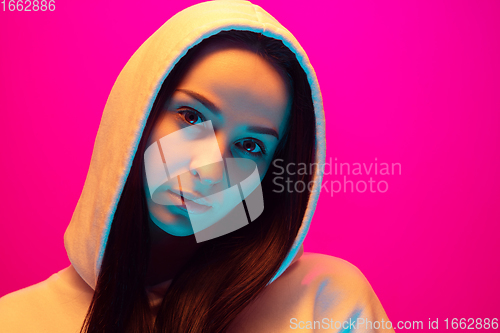 Image of Caucasian beautiful woman\'s portrait isolated on pink studio background in multicolored neon light