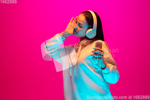 Image of Caucasian beautiful woman\'s portrait isolated on pink studio background in multicolored neon light