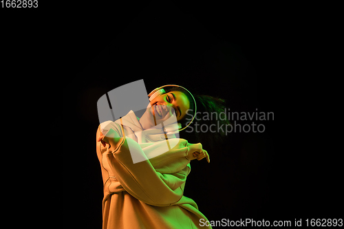 Image of African-american woman\'s portrait isolated on dark studio background in orange-green neon light