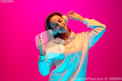 Image of Caucasian beautiful woman\'s portrait isolated on pink studio background in multicolored neon light