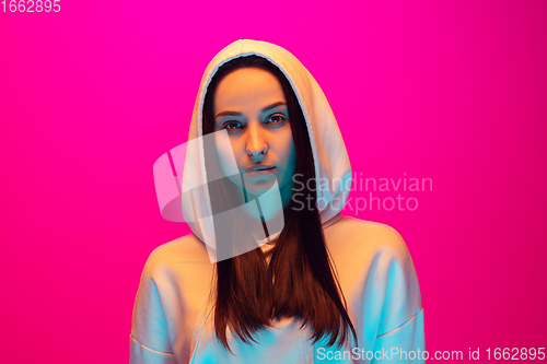 Image of Caucasian beautiful woman\'s portrait isolated on pink studio background in multicolored neon light