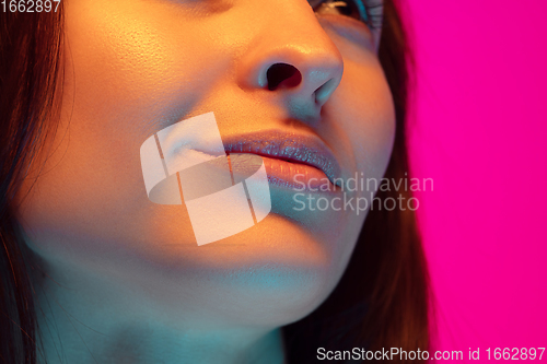 Image of Caucasian beautiful woman\'s portrait isolated on pink studio background in multicolored neon light