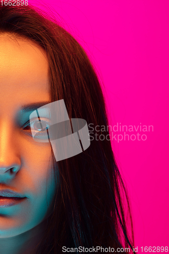 Image of Caucasian beautiful woman\'s portrait isolated on pink studio background in multicolored neon light