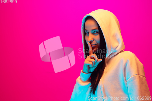 Image of Caucasian beautiful woman\'s portrait isolated on pink studio background in multicolored neon light