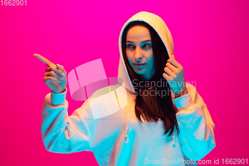 Image of Caucasian beautiful woman\'s portrait isolated on pink studio background in multicolored neon light