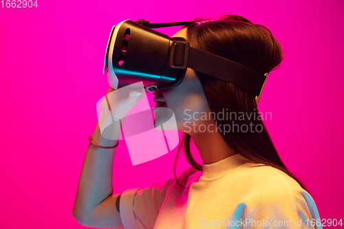 Image of Caucasian beautiful woman\'s portrait isolated on pink studio background in multicolored neon light