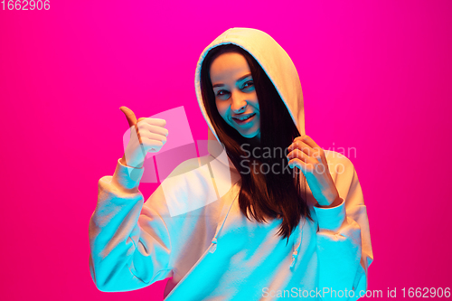 Image of Caucasian beautiful woman\'s portrait isolated on pink studio background in multicolored neon light