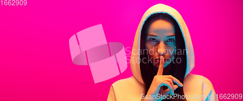 Image of Caucasian beautiful woman\'s portrait isolated on pink studio background in multicolored neon light