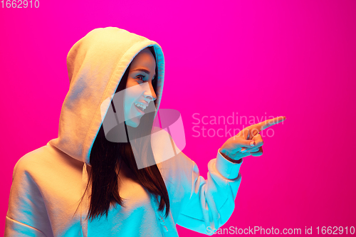 Image of Caucasian beautiful woman\'s portrait isolated on pink studio background in multicolored neon light