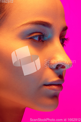 Image of Caucasian beautiful woman\'s portrait isolated on pink studio background in multicolored neon light