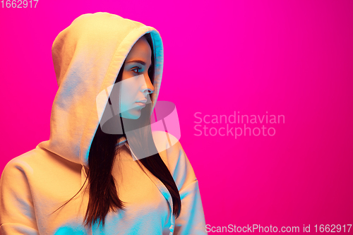 Image of Caucasian beautiful woman\'s portrait isolated on pink studio background in multicolored neon light