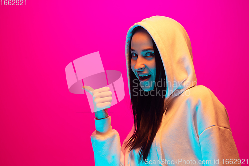 Image of Caucasian beautiful woman\'s portrait isolated on pink studio background in multicolored neon light