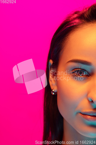 Image of Caucasian beautiful woman\'s portrait isolated on pink studio background in multicolored neon light