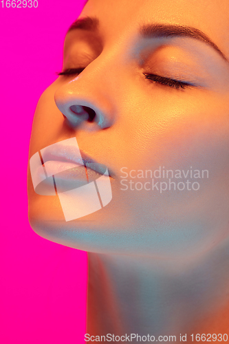 Image of Caucasian beautiful woman\'s portrait isolated on pink studio background in multicolored neon light