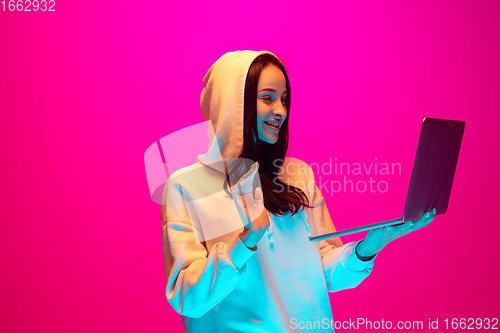 Image of Caucasian beautiful woman\'s portrait isolated on pink studio background in multicolored neon light