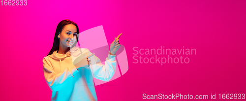 Image of Caucasian beautiful woman\'s portrait isolated on pink studio background in multicolored neon light