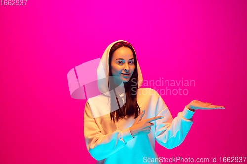 Image of Caucasian beautiful woman\'s portrait isolated on pink studio background in multicolored neon light